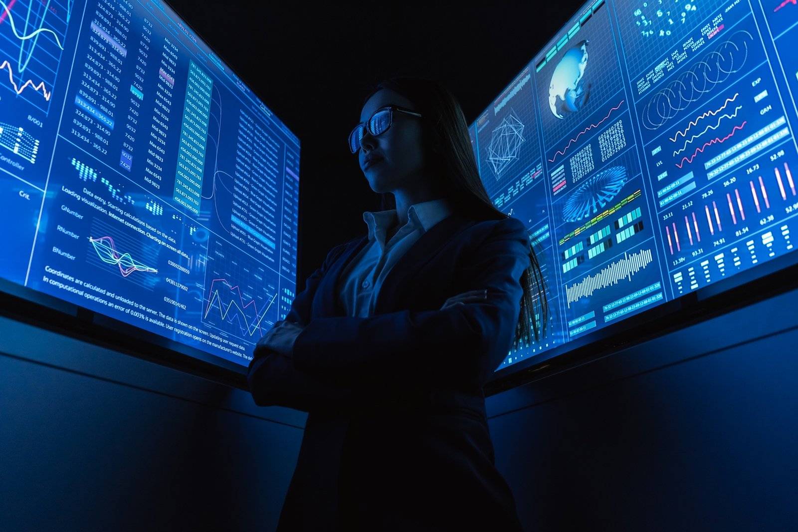 The businesswoman standing near the blue monitor.
